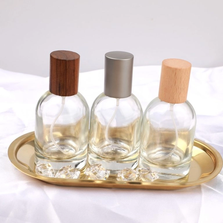 Three clear mini perfume bottles with wood and metal caps on a gold tray