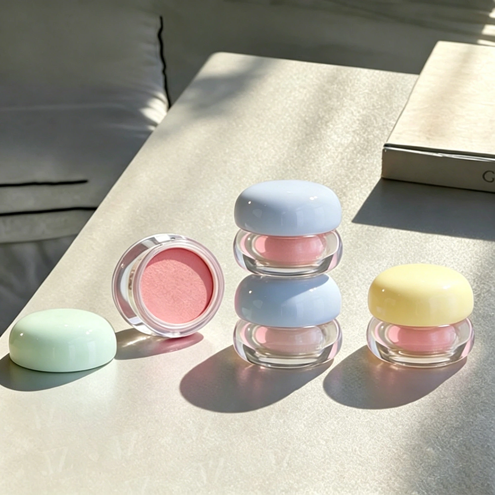 Pastel round cosmetic containers with domed caps and an open pink makeup pan